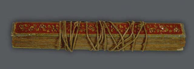 The pothi is protected by wooden boards and bound by the string that passes throught the leaves.